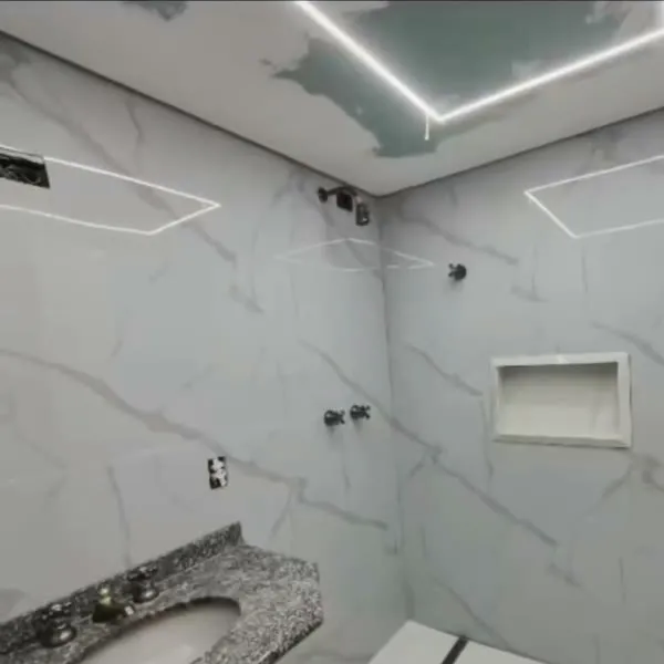 Banheiro com revestimento marmorizado claro, bancada, nicho e iluminação de LED.