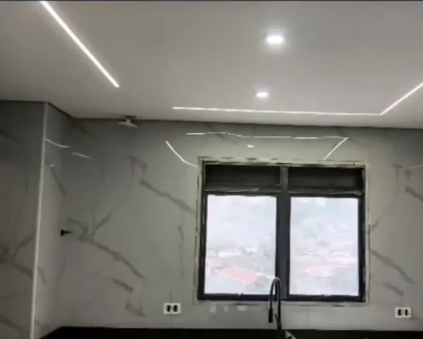 Cozinha com janela escura, revestimento marmorizado e perfil de LED no teto.