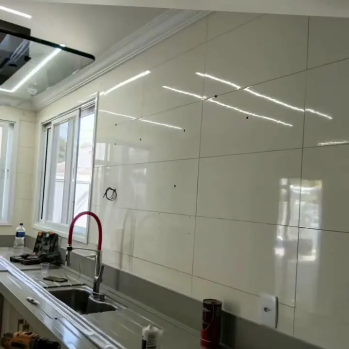 Parede de cozinha revestida, com bancada e linhas de LED.